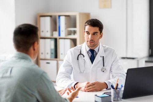 medicine, healthcare and people concept - doctor talking to male patient at medical office in hospital